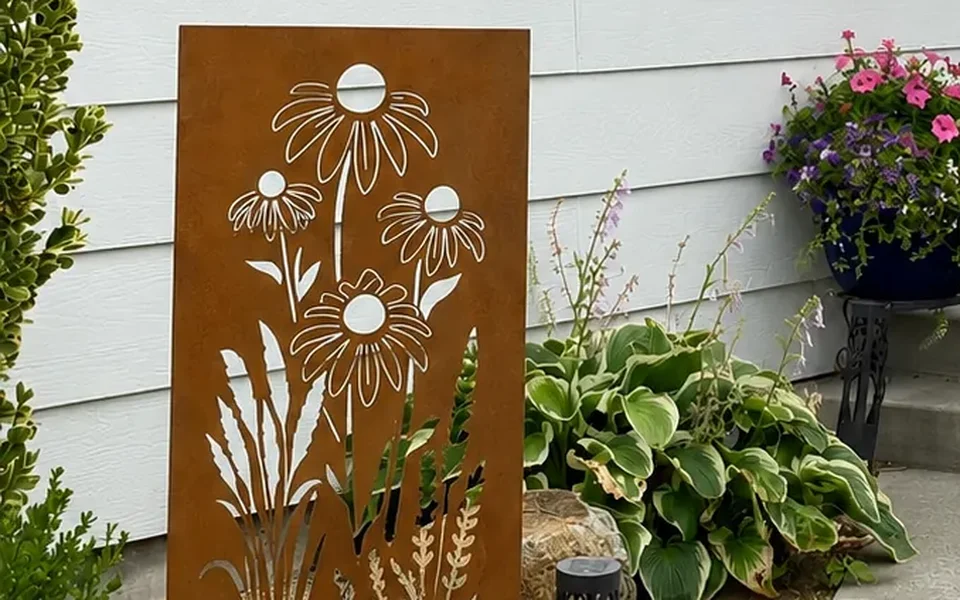 Tall rusted-steel garden panel with a daisy and wildflower cutout standing beside a house entry
