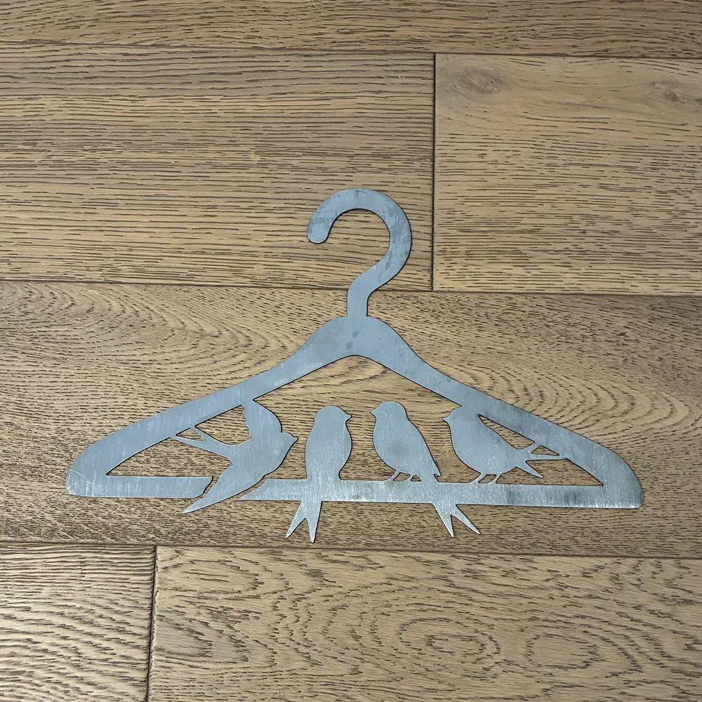Raw steel clothes hanger cut-out with four birds on a branch.