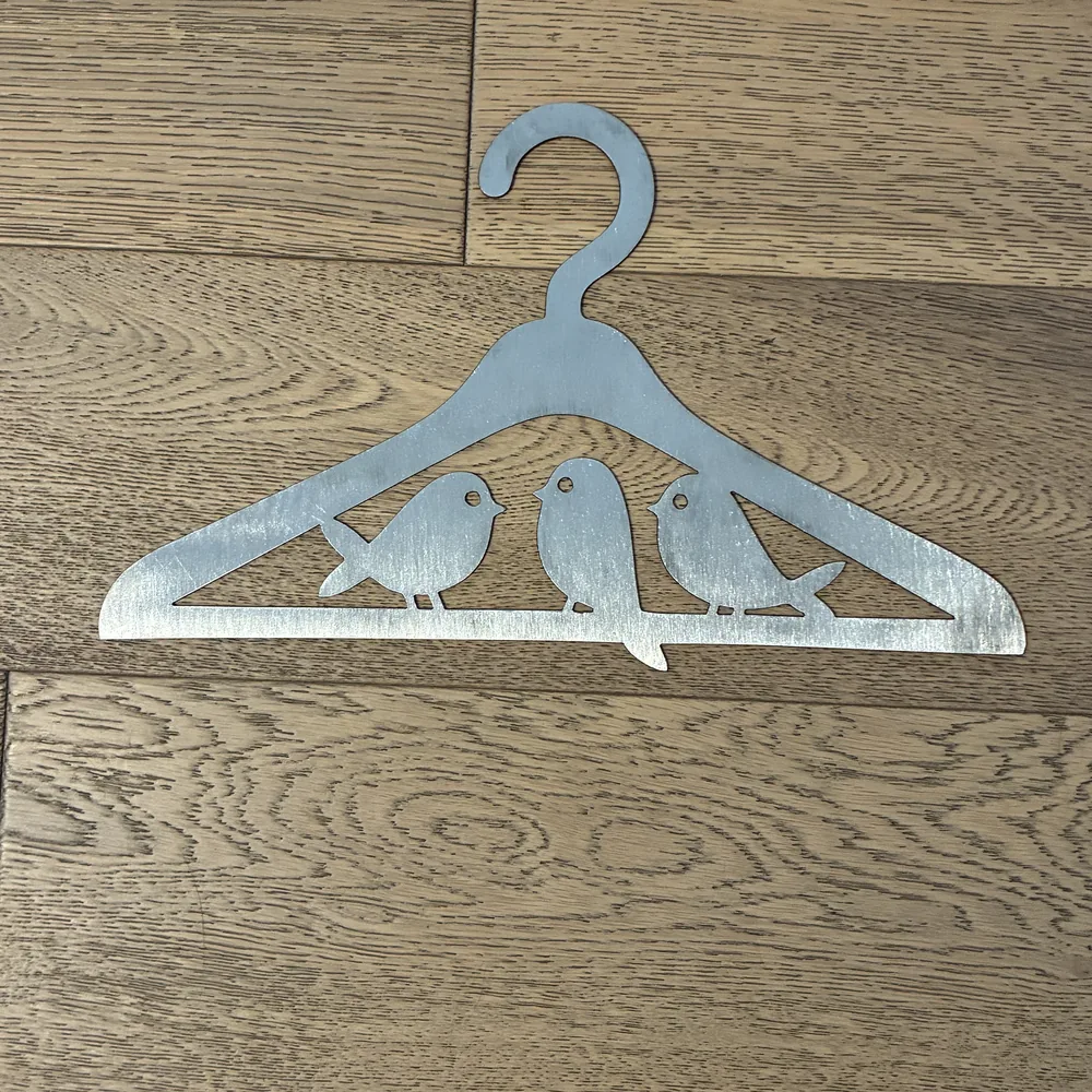 Raw steel clothes hanger cut-out with three birds on a branch.