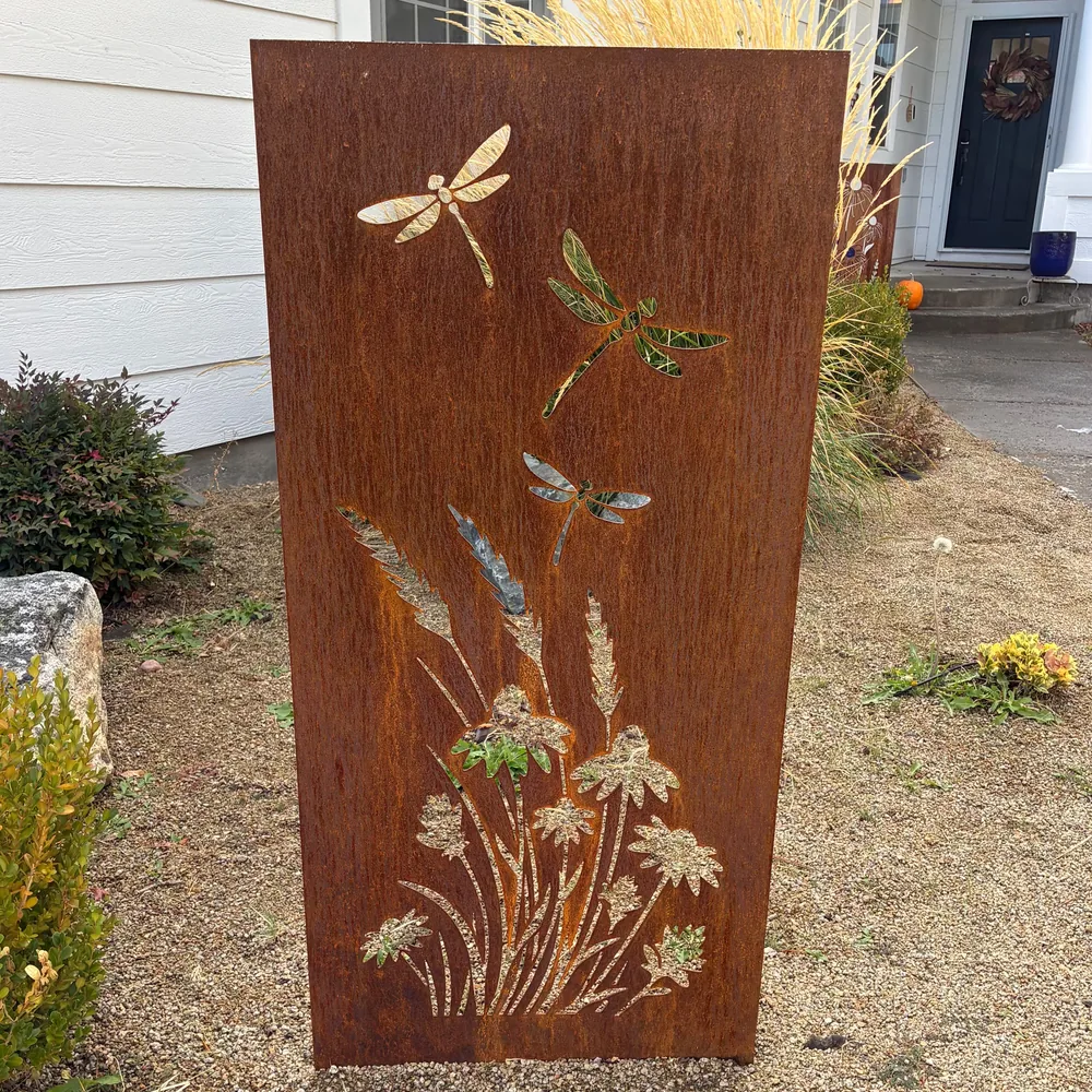Rusted steel garden panel with dragonflies over wildflowers and grasses.