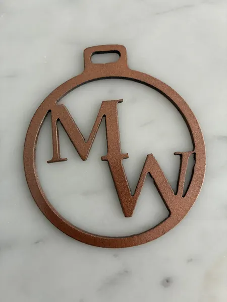 Round copper-finish ornament with an MW monogram