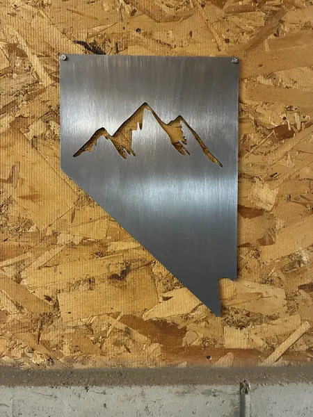 Brushed steel plaque in the shape of Nevada with a mountain cutout